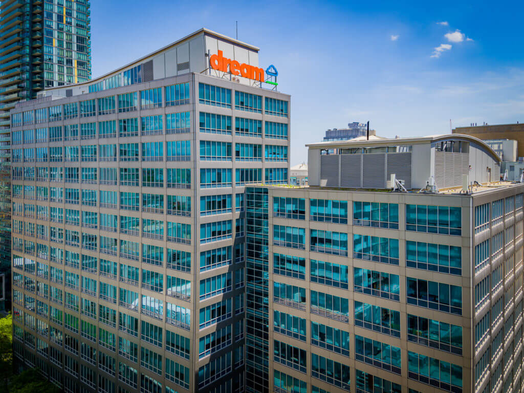 Blue skies drone shot of Dream's 30 Adelaide Street East office with the orange Dream logo on the rooftop.