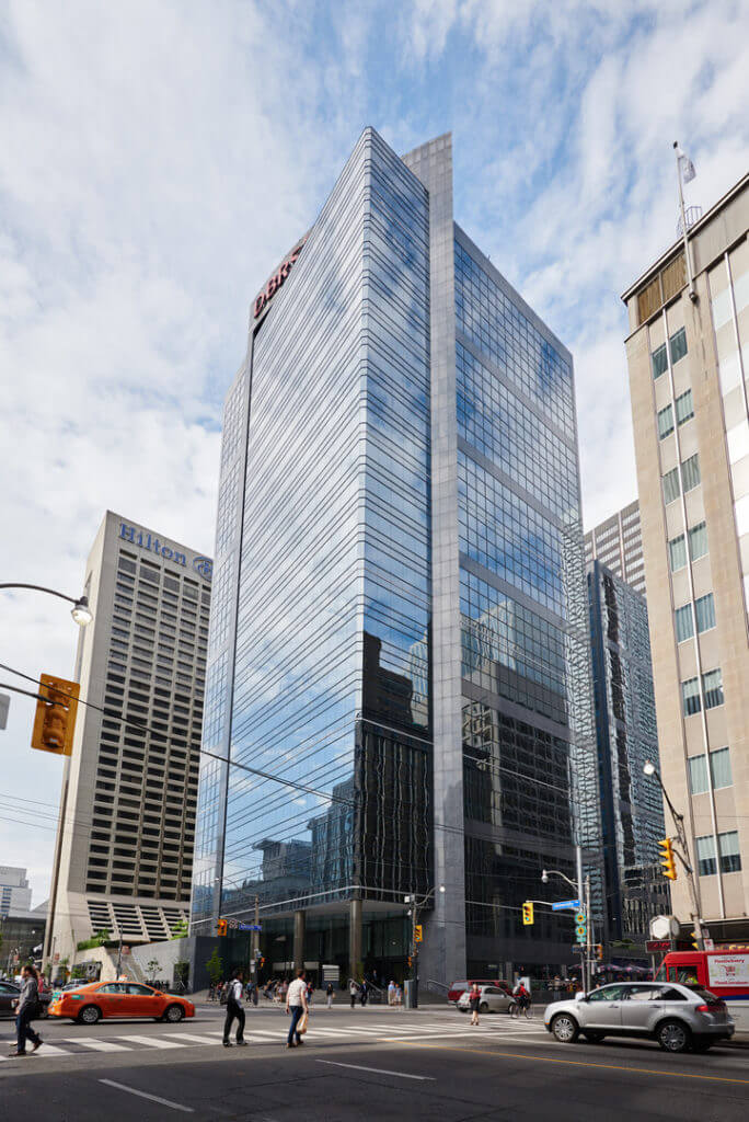 Full length shot of Dream Office's Adelaide Place with mirrored exterior and people crossing the street intersection.