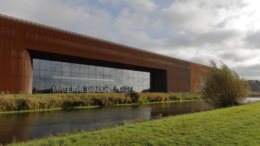 Dream Industrial Building in Ede, Netherlands on a cloudy day beside the river with green grass.